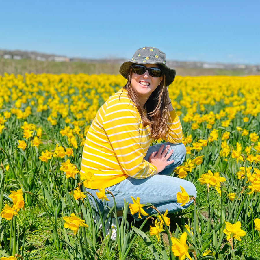 Woman in yellow and white striped shirt in daffodil field