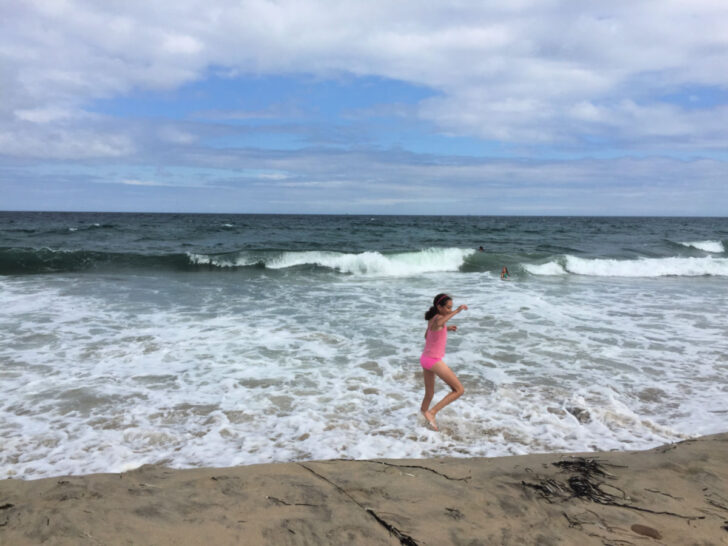 Girl in pink bathing suit play in waves